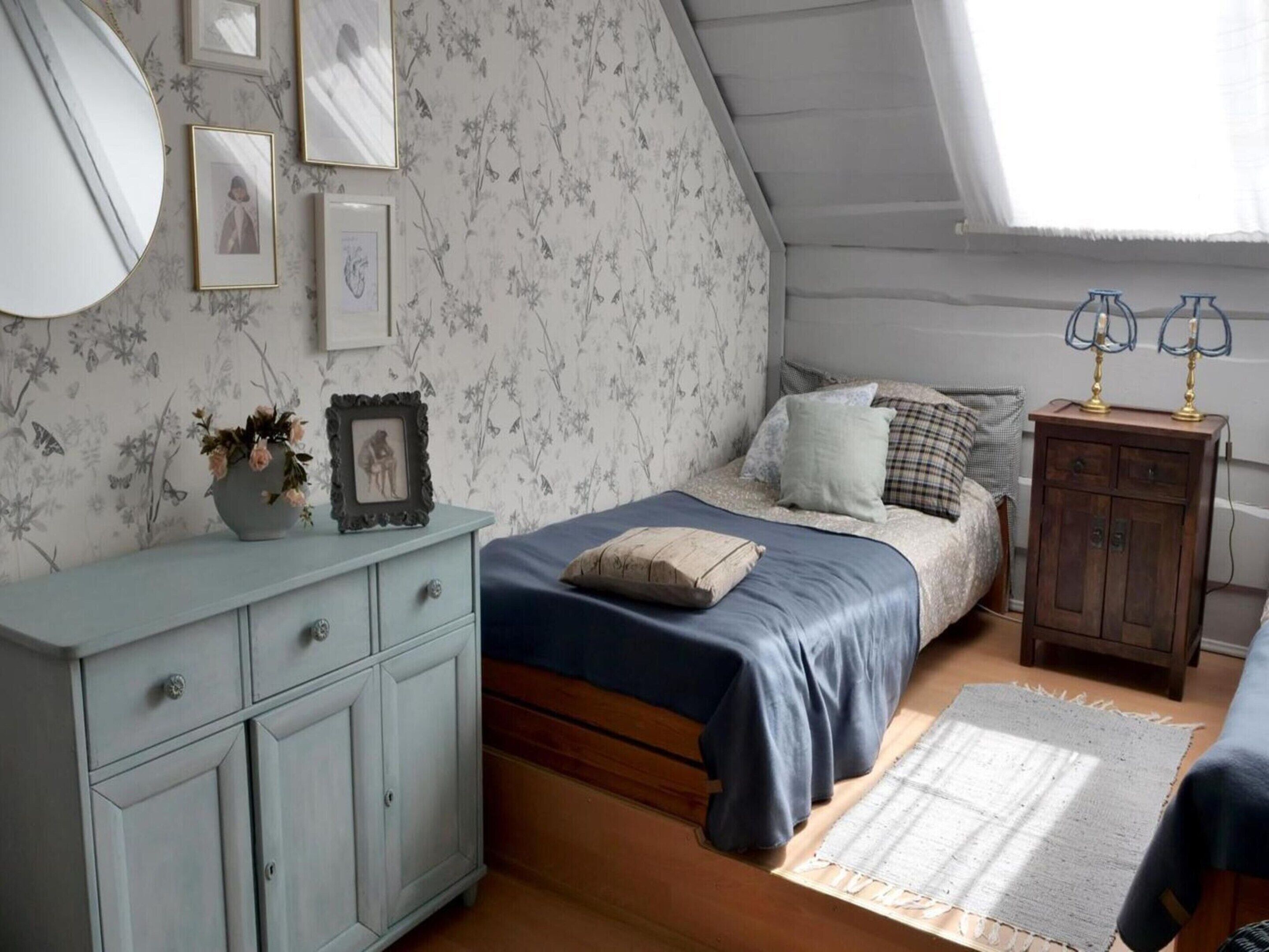 A bedroom with a bed, a dresser, a mirror, and a window.