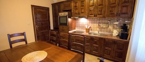 A kitchen with wooden cabinets, a dining table with chairs, and a built-in oven.