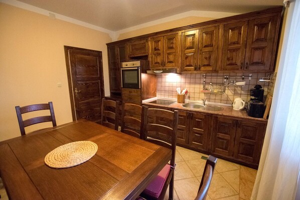 Una cocina con armarios de madera, una mesa de comedor con sillas y un horno empotrado.