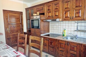 A kitchen with wooden cabinets, a built-in oven, a sink, and a chair. - Villa in Starigrad Near Paklenica National Park (Starigrad)
