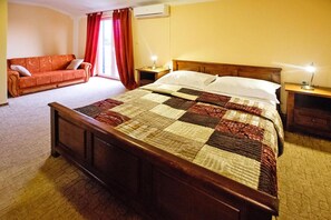 Un dormitorio con una cama de madera, un sofá rojo y una mesita de noche con una lámpara.