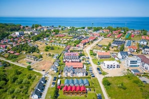 An aerial view of a coastal town with a mix of residential and commercial buildings, including a prominent hotel with a red roof and a large parking area. - Comfortable Holiday Cottage in Jaroslawiec (Postomino)