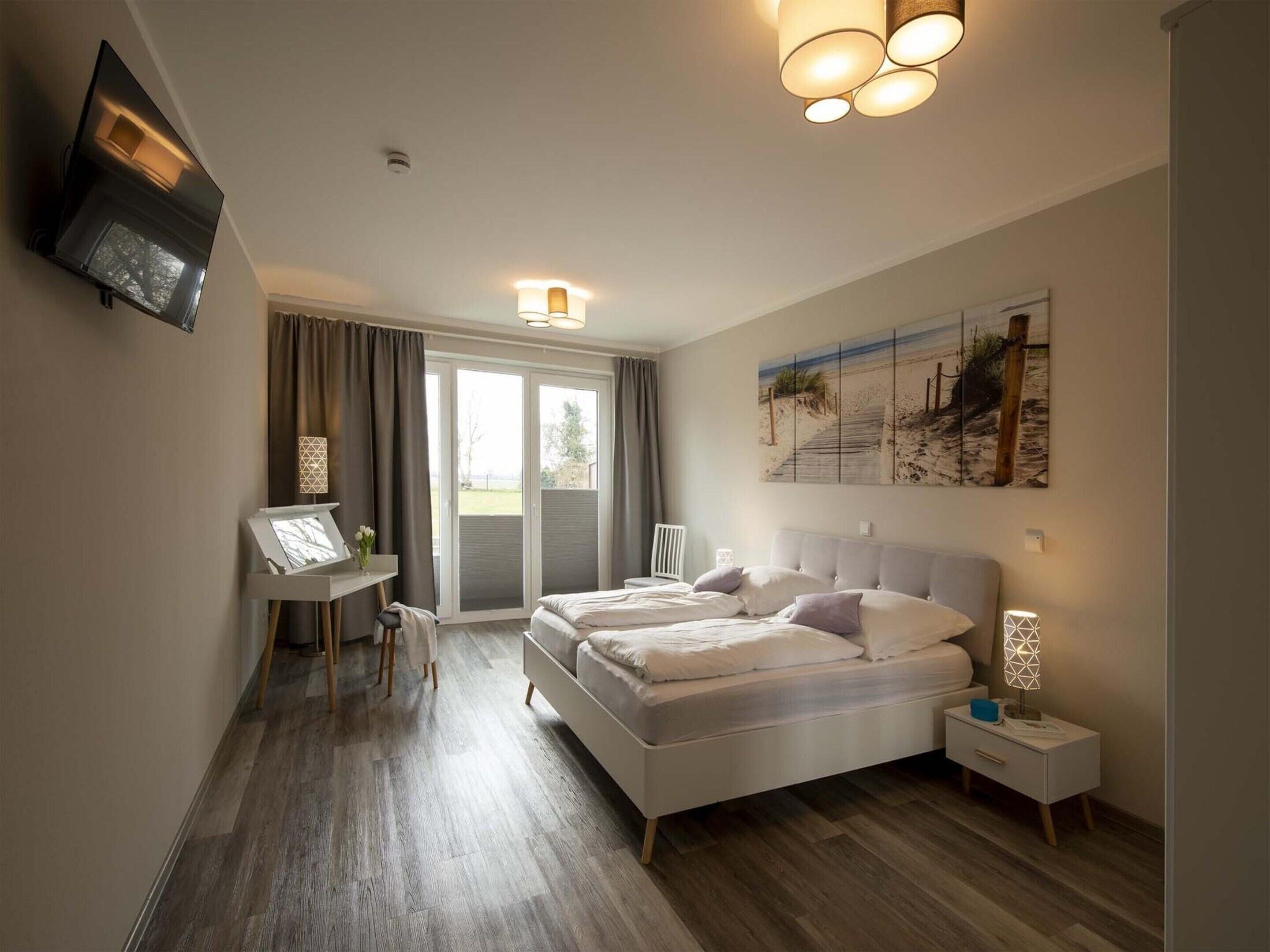 A modern bedroom with a large bed, a desk, and a painting on the wall.