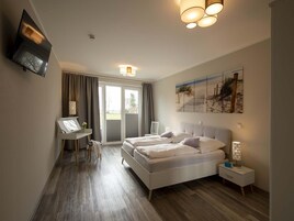 A modern bedroom with a large bed, a desk, and a painting on the wall.