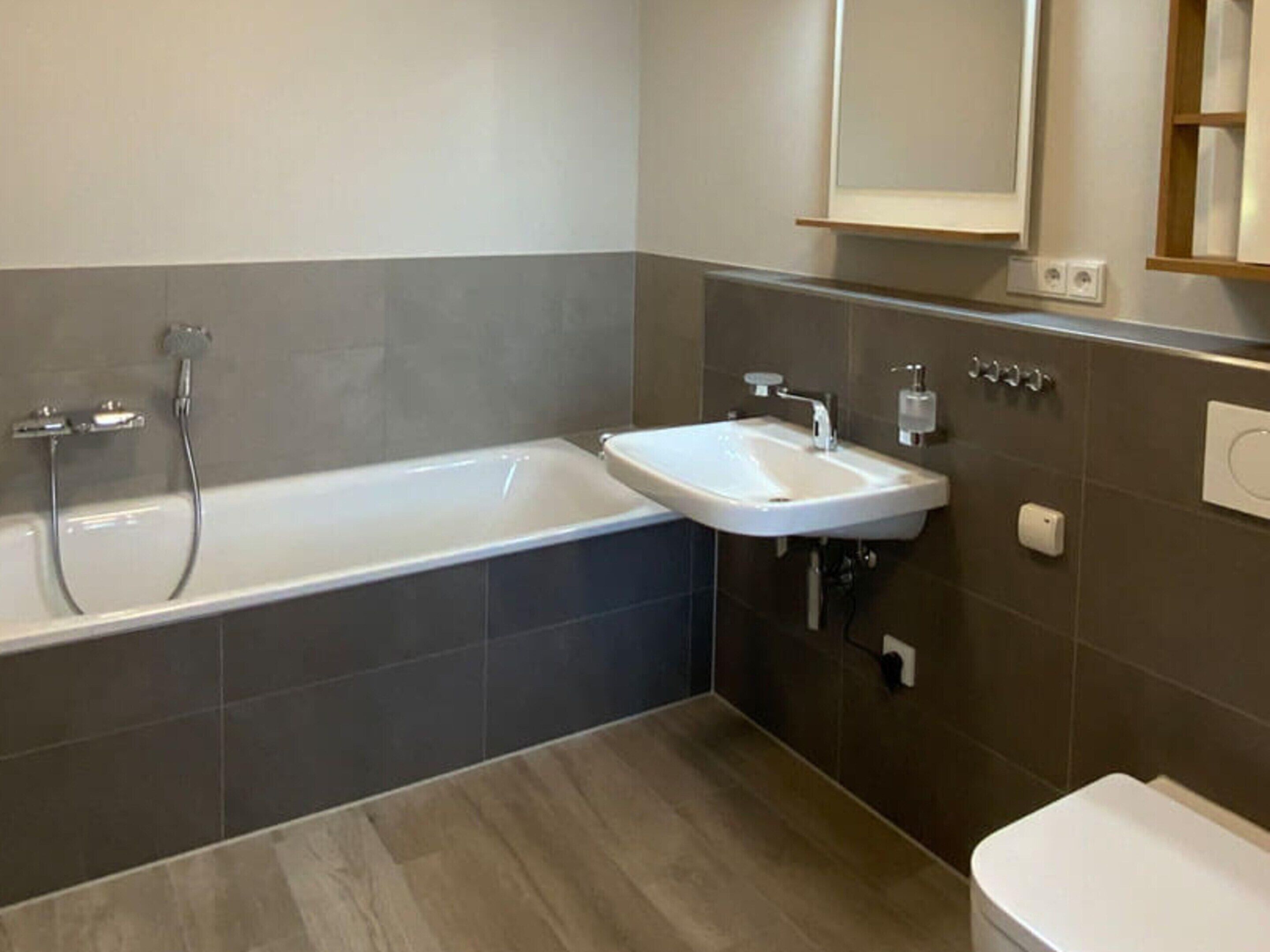 A modern bathroom with a bathtub, a sink, and a toilet.