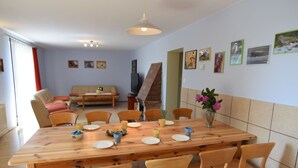 A dining area with a wooden table and chairs, a sofa, and a TV in the background. - Large House by the Lake, Kashubia (Parchowo)