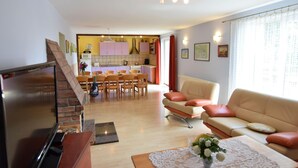 A living room with a TV, sofa, and a dining area with chairs and a table. - Large House by the Lake, Kashubia (Parchowo)