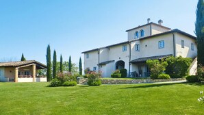 Un grand bâtiment à deux étages, doté d’un toit en tuiles, de fondations en pierre et d’une pelouse bien entretenue.