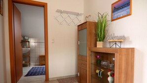 A hallway with a wooden cabinet, a blue rug, and a welcome sign. - Appartementhaus Nicole, Zinnowitz (Zinnowitz)