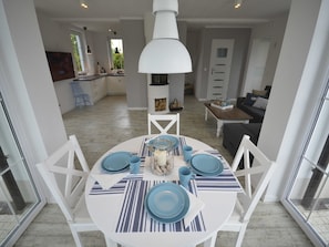 A dining area with a round table set for four, white chairs, and a white pendant light.