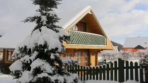 A wooden cabin with a sloped roof, a balcony, and a snow-covered tree in the foreground. - Blockhouse in the Fuchsbau, Bad Sachsa (Bad Sachsa)