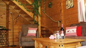 A cozy log cabin interior with a wooden coffee table, two armchairs with checkered pillows, a floor lamp, and a bottle of wine. - Blockhouse in the Fuchsbau, Bad Sachsa (Bad Sachsa)