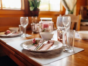 A dining table set with plates, cutlery, glasses, and a vase with a flower.