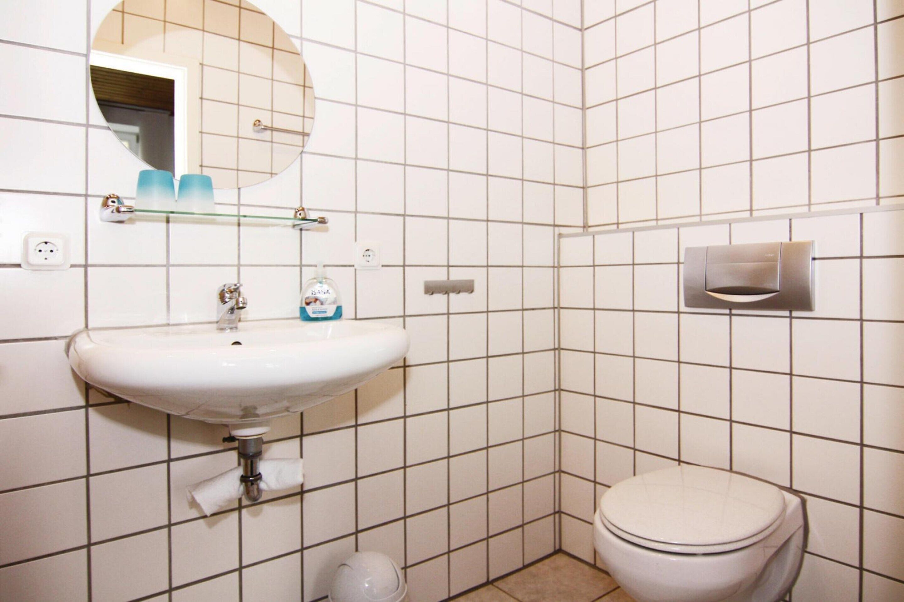 A bathroom with a white sink, mirror, and toilet.