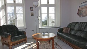 A living room with two leather sofas, a wooden coffee table, and a patterned rug. - Ferienwohnung im Gutshaus Schulenbrook (Metelsdorf)