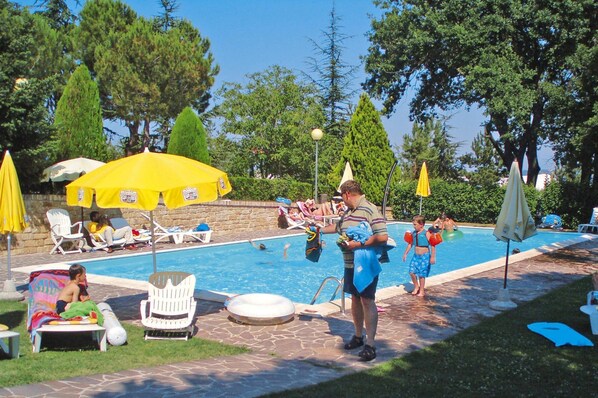 Un espace piscine aménagé avec des chaises longues et des parasols.