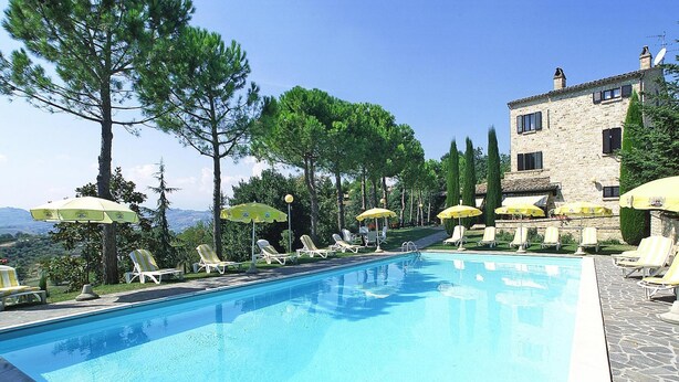 A swimming pool with sun loungers and umbrellas, surrounded by trees and a stone building. - Hotel in Marche With Scenic Hiking Trails (Montelparo)
