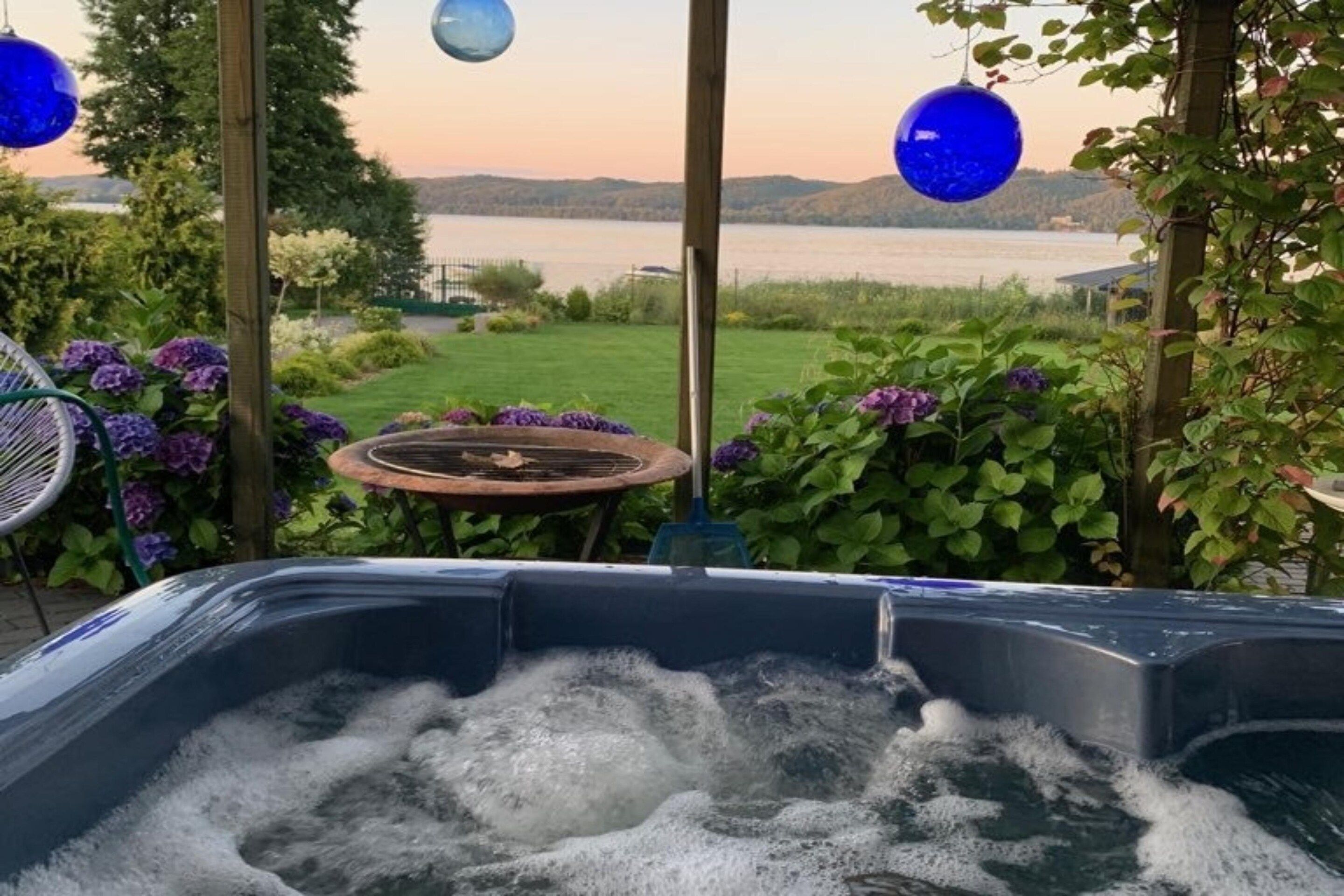 A hot tub with a view of a lake and hills.