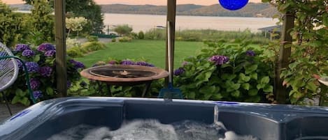 A hot tub with a view of a lake and hills.