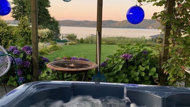 Un bain à remous avec vue sur un lac et des collines en arrière-plan.