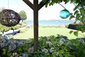 A garden with hydrangea bushes, a wooden pergola, and a view of a lake. - House With Private Beach by the Lake, Whirlpool (Gniewino)