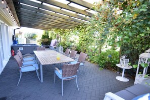 An outdoor patio with a wooden pergola, a table with chairs, and a garden with ivy and flowers. - House With Private Beach by the Lake, Whirlpool (Gniewino)