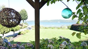 Un jardin agrémenté de buissons d’hortensias, d’une pergola en bois et offrant une vue sur un lac.