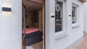 A modern hotel room with a bed, a small window, and a door leading to the outside. - Ferienwohnung in Tonning (Toenning)