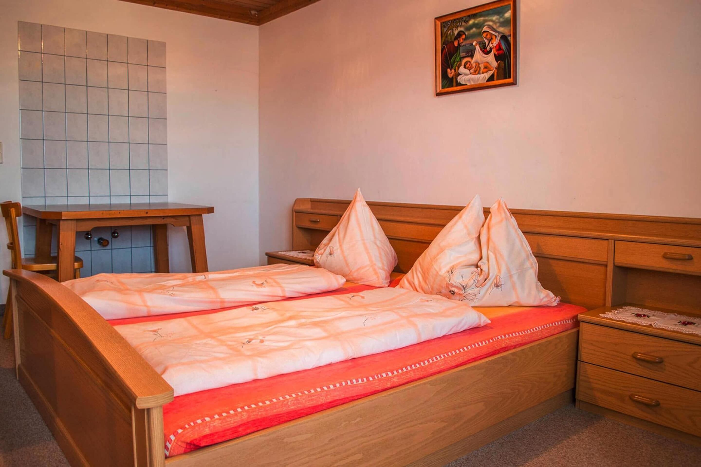 Un dormitorio con una cama de madera, un escritorio pequeño y una mesita de noche.