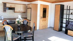 A compact kitchen with wooden cabinets, a dining table with chairs, and a built-in TV. - Apartment in Mittersill Near Kitzski Lift (Mittersill)