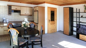 A compact kitchen with wooden cabinets, a dining table with chairs, and a built-in bookshelf. - Apartment in Mittersill Near Kitzski Lift (Mittersill)