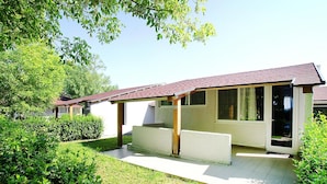 A single-story house with a covered porch, a sliding glass door, and a small front yard with a hedge.