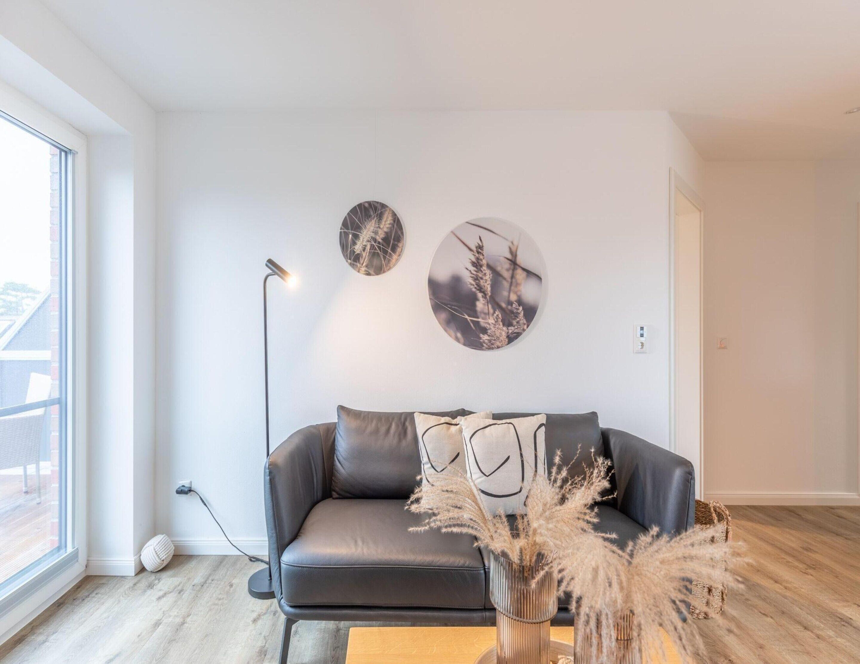 Una sala de estar moderna con un sofá de cuero, una mesita de centro y dos obras de arte circulares colgadas en la pared.