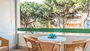 A balcony with wicker chairs and a table, overlooking a building and trees. - Condominio Vera Cruz in Bibione-ex TUI (San Michele al Tagliamento)