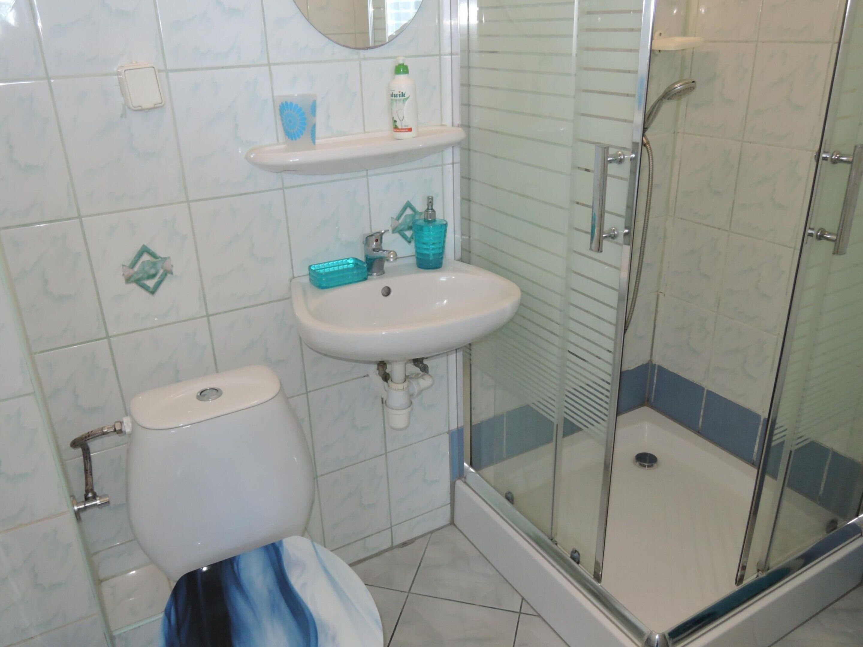 A bathroom with a toilet, sink, and glass shower enclosure.