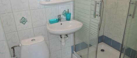 A bathroom with a toilet, sink, and glass shower enclosure.