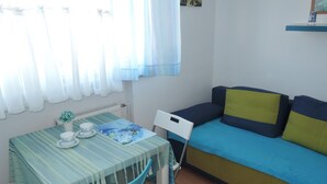 Une petite pièce avec une table et des chaises, un canapé et un radiateur.