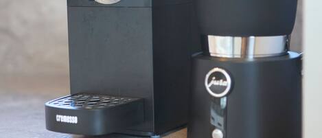 Máquina de café com bandeja coletora e jarra em uma bancada de cozinha.
