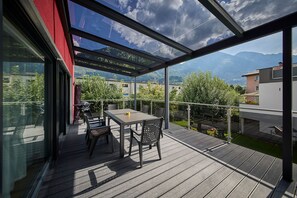 Un espacio al aire libre techado con una mesa y sillas, con vistas a un paisaje montañoso.