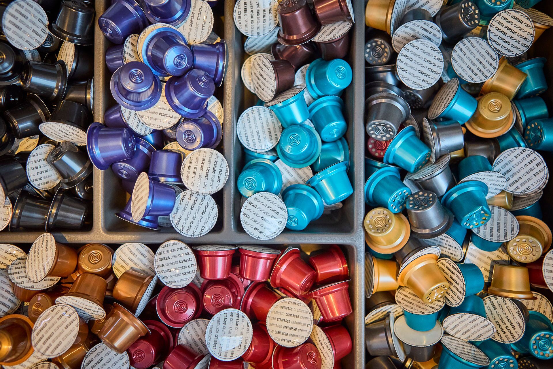 A collection of variously colored and shaped containers, likely for storage or packaging, arranged in a compartmentalized structure.