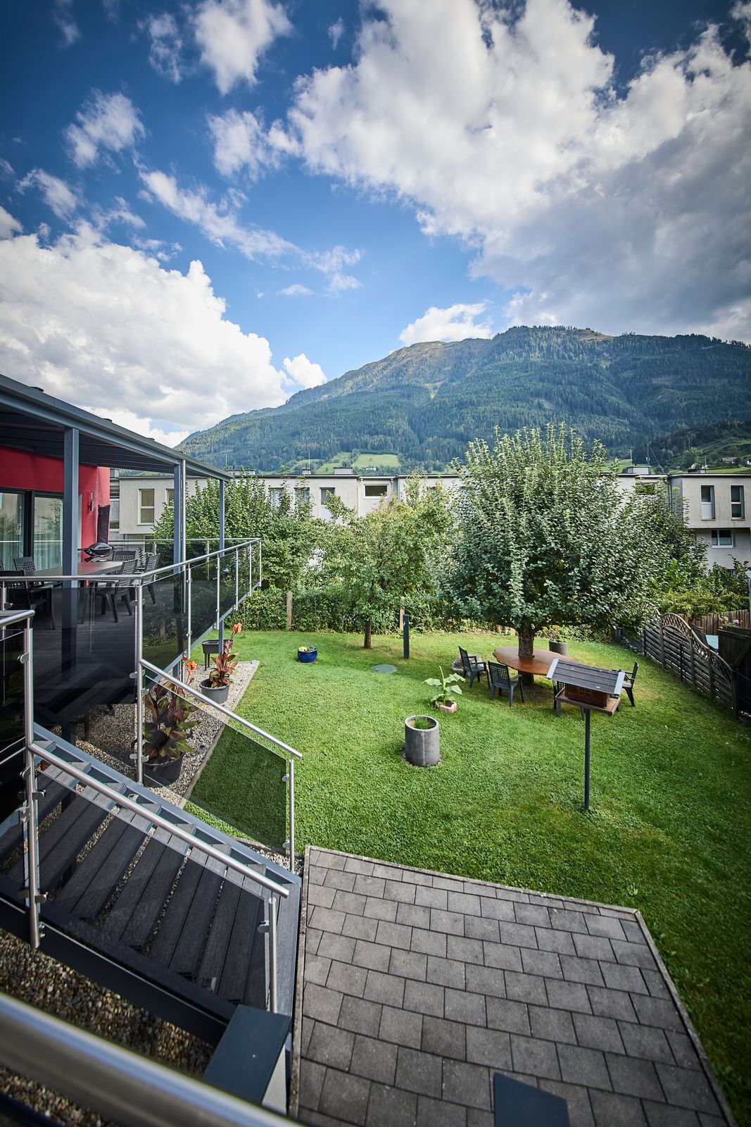 A residential backyard with a patio, a dining table, and a view of a mountain.