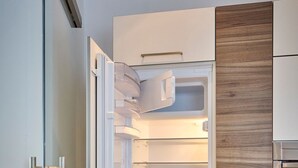 Eine moderne Küche mit integriertem Kühlschrank, einer Holzpaneel-Verkleidung und einem Edelstahlbackofen.