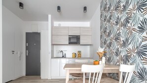A modern kitchen with white cabinets, a wooden dining table, and chairs. - Apartment in Rewal Near Baltic Sea Beach (Rewal)
