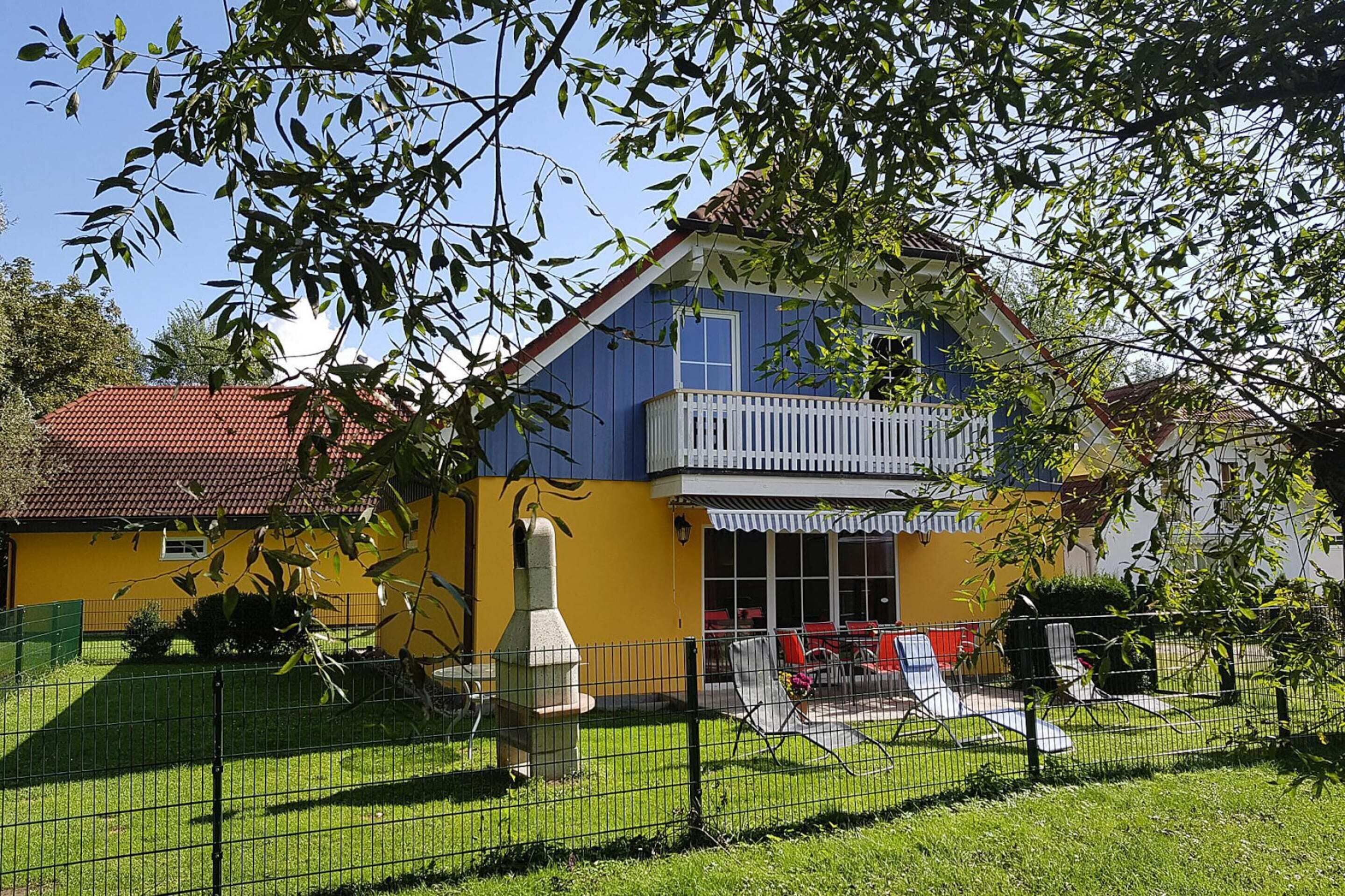 A two-story building with a balcony, a fenced yard, and outdoor seating.