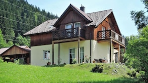 A two-story wooden house with a balcony, surrounded by lush greenery and a forested hillside. - Chalet in Radstadt Near Ski Slopes & Spa (Radstadt)