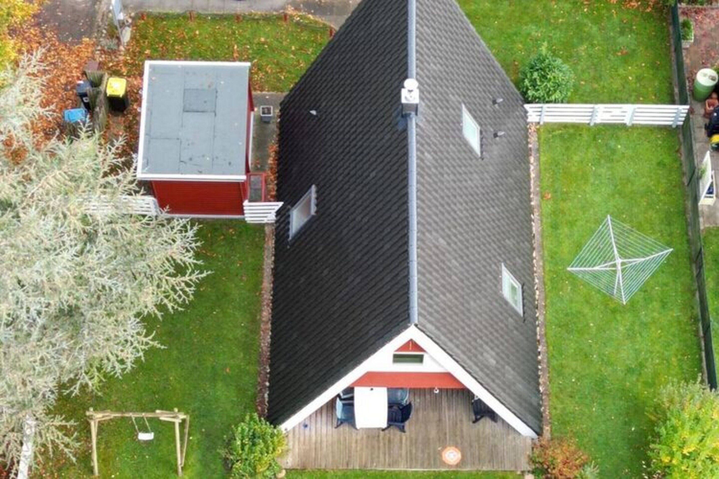 A residential house with a sloped roof, a fenced yard, and a swing set.