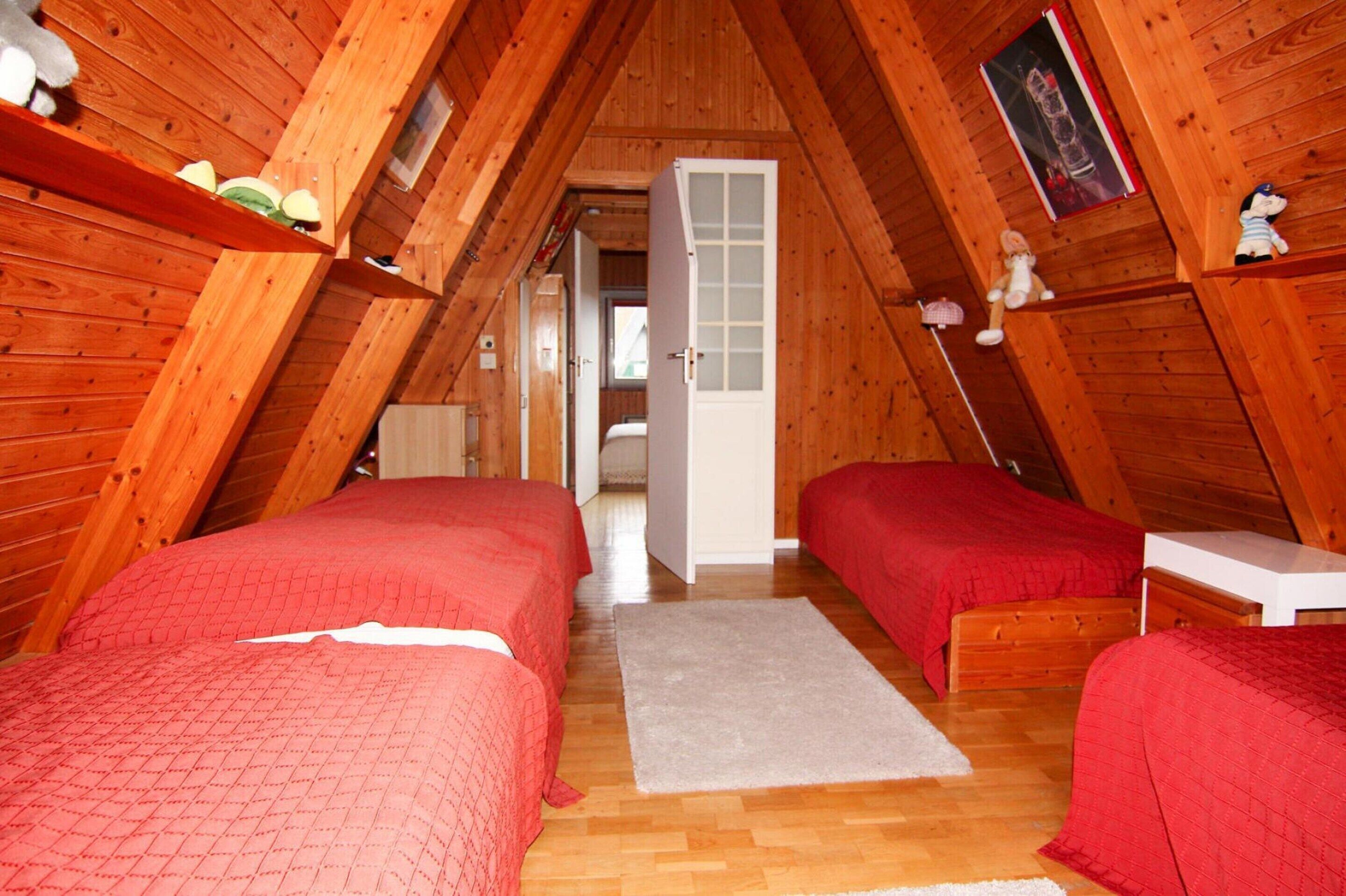 Una camera da letto mansardata accogliente con due letti, pareti in legno e una piccola finestra.