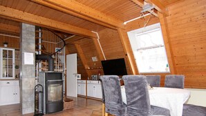 Tunnelmallinen, puinen sisustus, jossa on ruokailutila, keittiö ja takka.