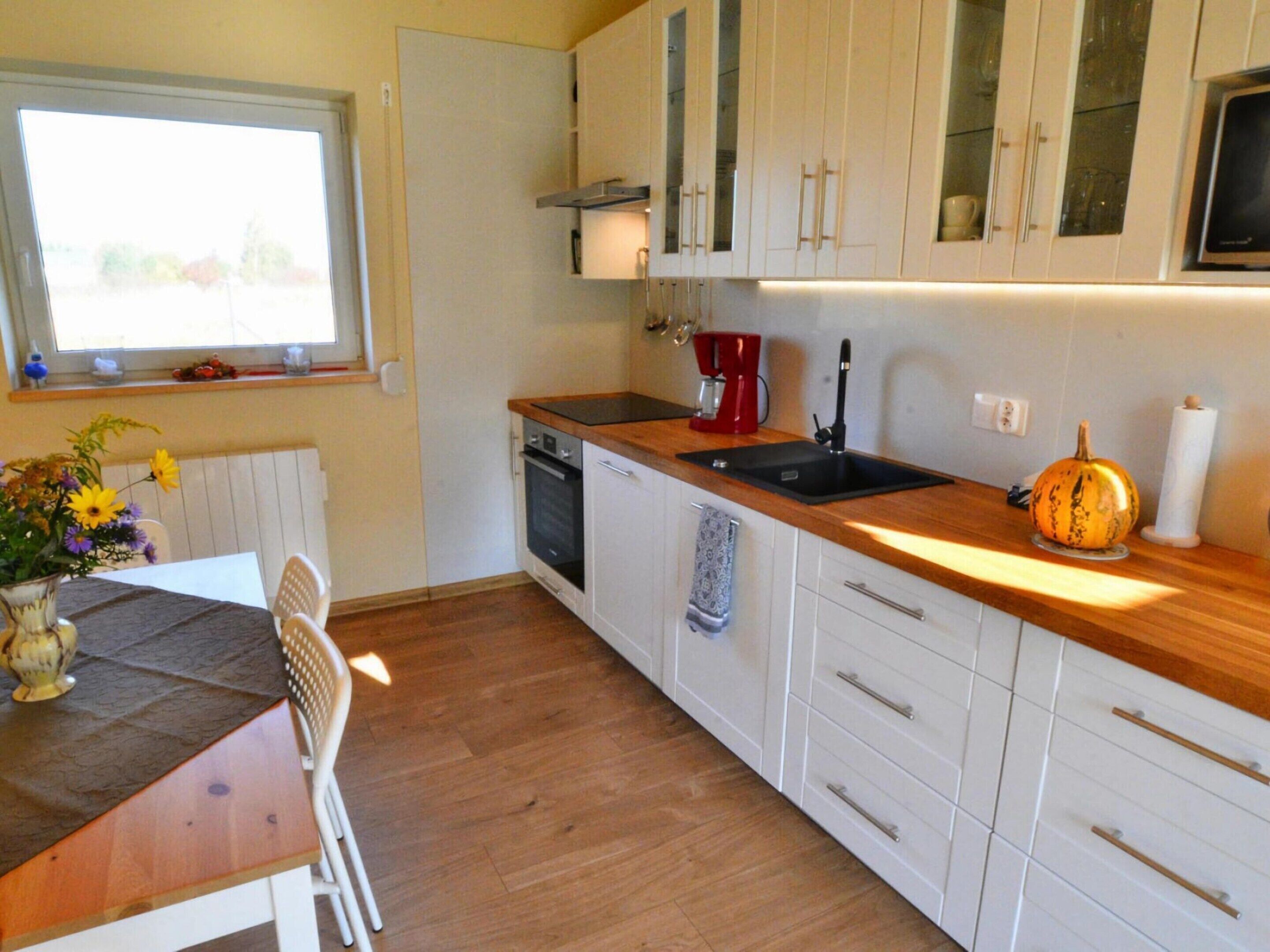 A kitchen with white cabinets, a wooden countertop, a sink, a coffee maker, and a pumpkin decoration.
