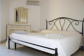 Un dormitorio con cama, mesita de noche, cómoda y espejo.